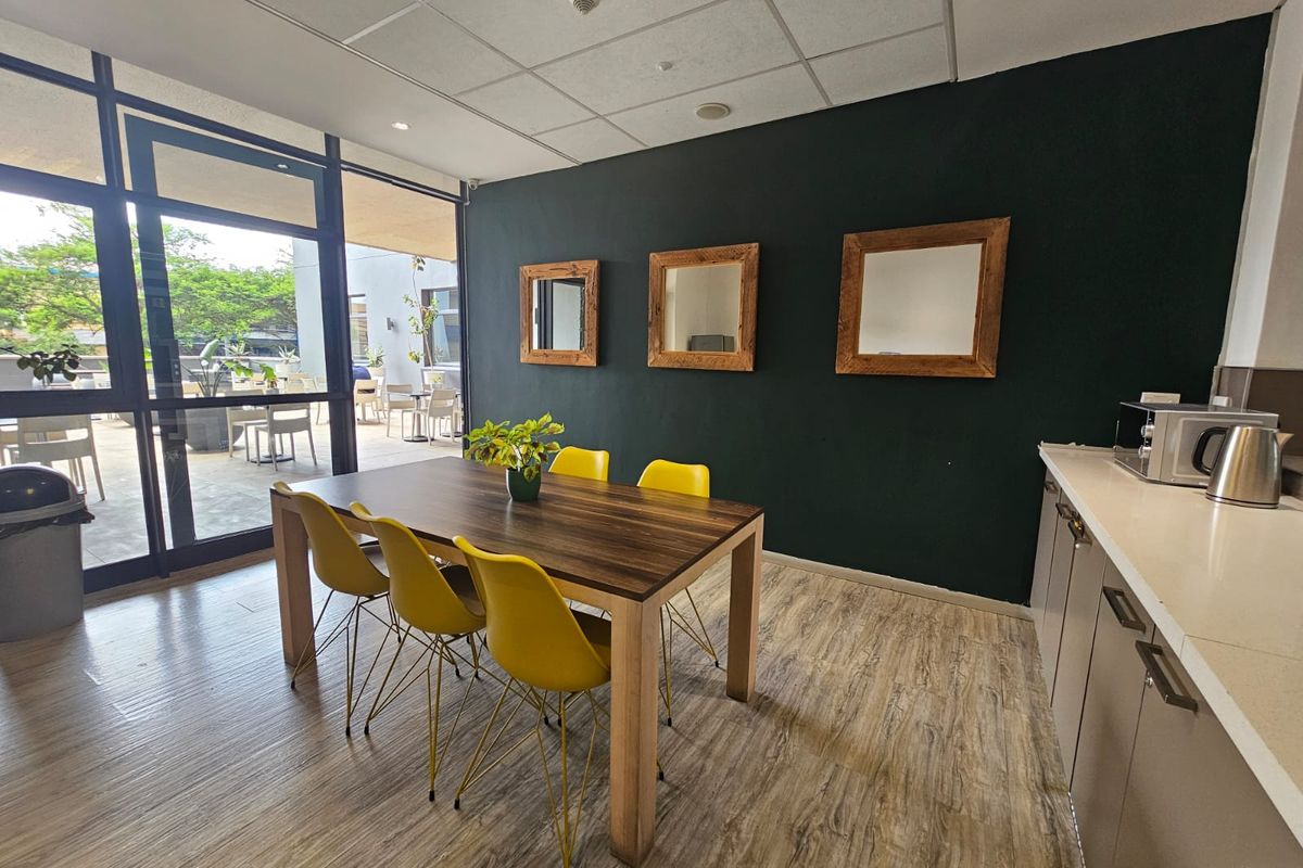A modern kitchen and dining area featuring built-in cabinetry, stone countertops, and large glass sliding doors leading to an outdoor patio space.