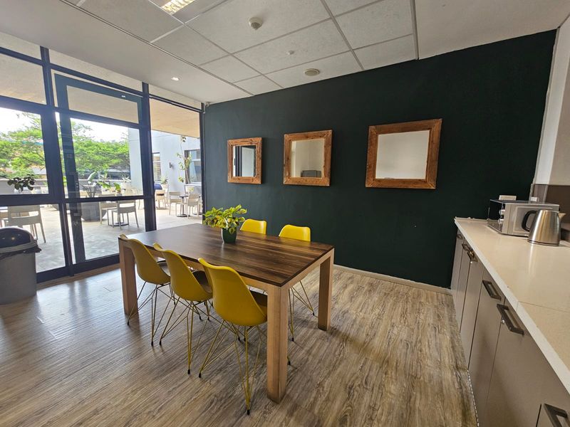 A modern kitchen and dining area featuring built-in cabinetry, stone countertops, and large glass sliding doors leading to an outdoor patio space.