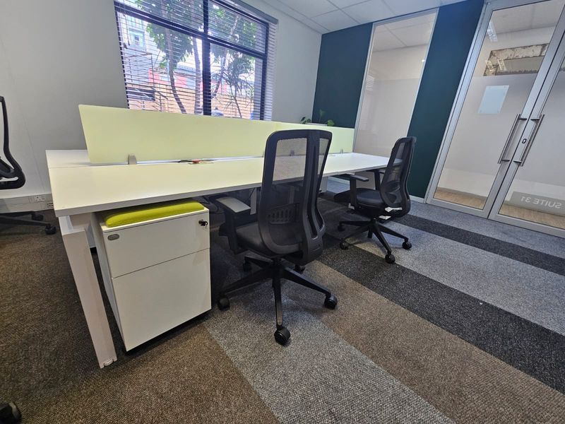 A modern office space featuring a built-in workstation with privacy screens, glass partitioning, and professional carpet tile flooring.