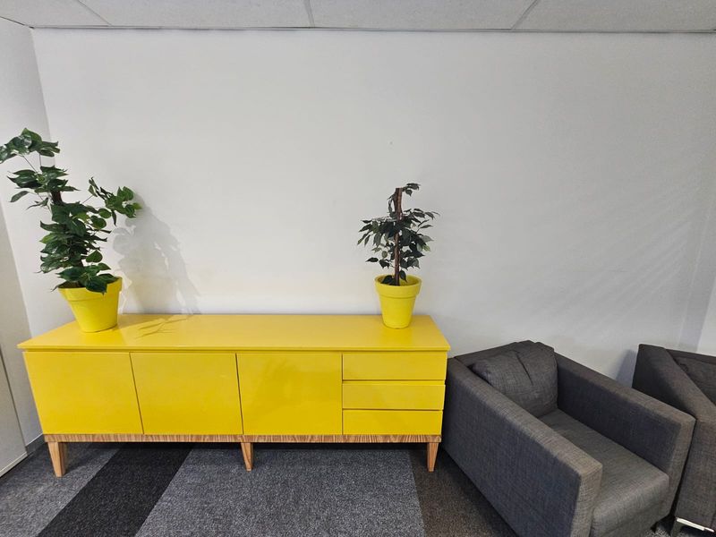 A functional office space featuring a suspended ceiling and carpeted flooring, providing a clean and professional environment for business operations.