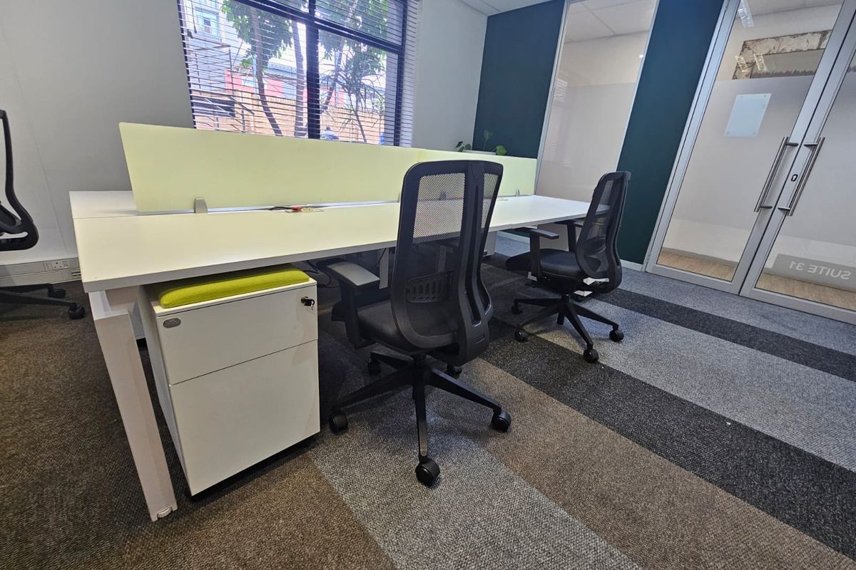 A modern office space featuring a built-in workstation with privacy screens, glass partitioning, and professional carpet tile flooring.
