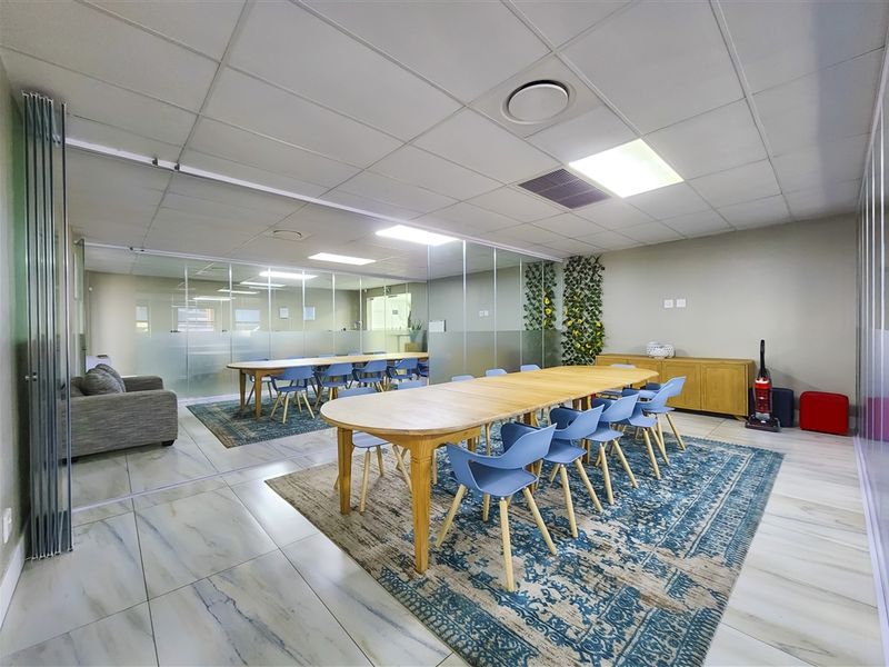 Modern office space featuring glass partition walls, suspended ceilings with recessed lighting, and polished tiled flooring, creating a bright and professional work environment.