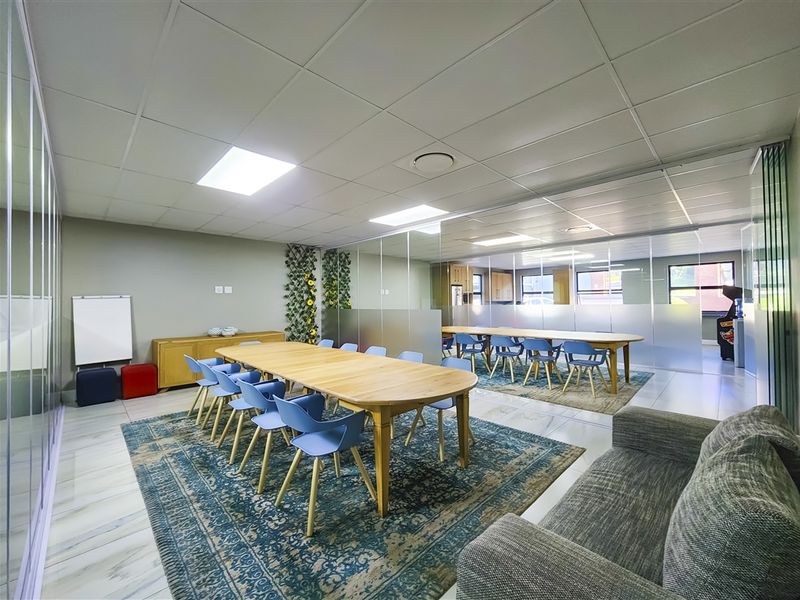 Modern office space featuring glass partitions, suspended ceilings with recessed lighting, and tiled flooring, creating a bright and professional collaborative work environment.