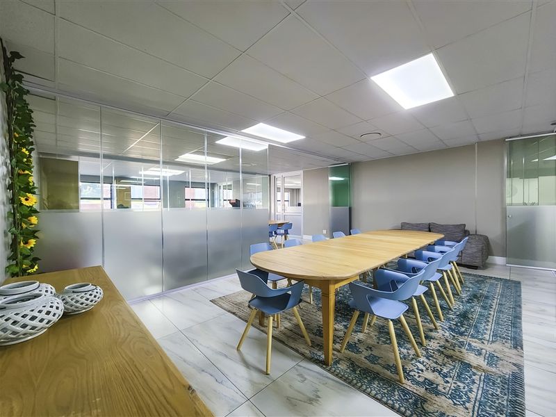 Modern office meeting room featuring glass partitions, suspended ceiling with recessed lighting, and polished tiled flooring.
