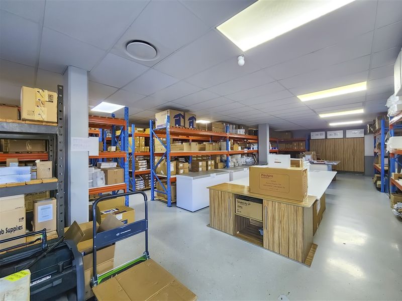 A functional utility and storage space featuring industrial shelving, durable epoxy flooring, and integrated cabinetry, suitable for office or warehouse operations.