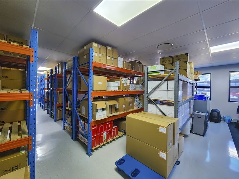 A well-maintained industrial storage area featuring durable epoxy flooring, suspended ceiling with recessed lighting, and extensive heavy-duty metal shelving units.