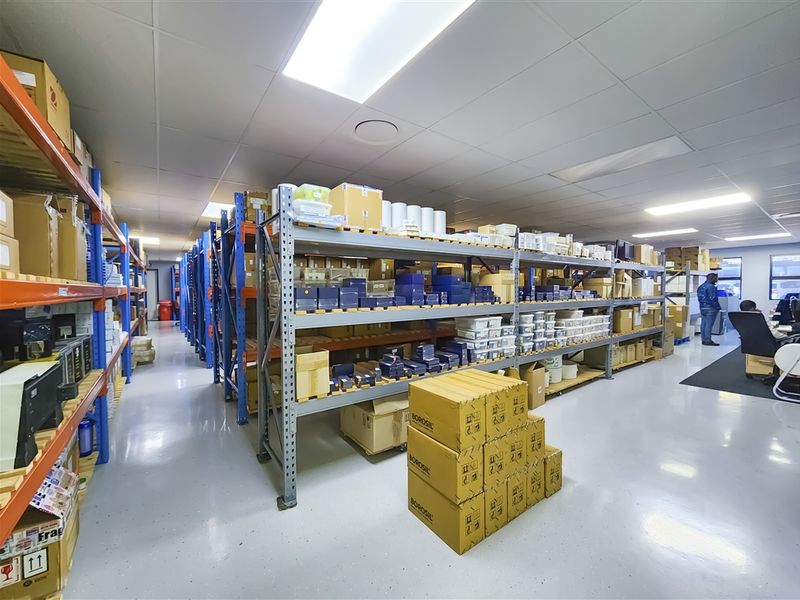 A functional warehouse or storage area featuring industrial shelving units, durable epoxy flooring, and a clean suspended ceiling with recessed lighting.