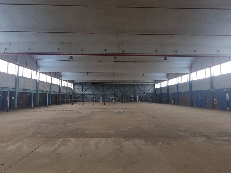 Expansive industrial warehouse space featuring high ceilings, large windows for natural light, and a durable concrete floor, suitable for various commercial or storage uses.