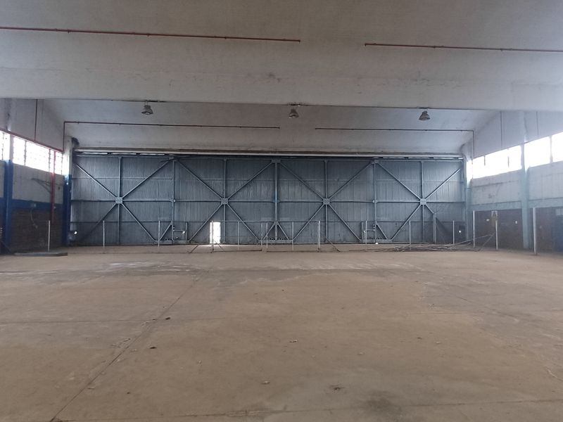 Spacious industrial warehouse featuring high ceilings, large hangar-style sliding doors, and expansive open floor area suitable for manufacturing or storage operations.