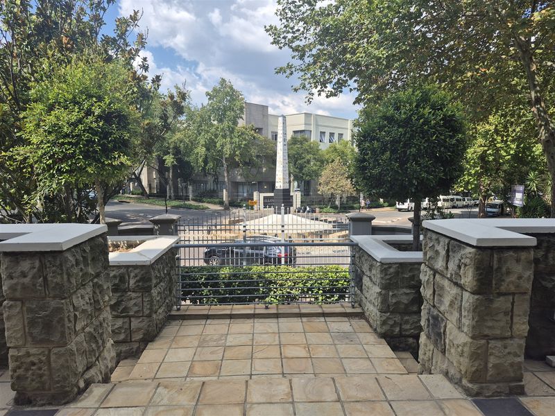 View from the entrance landing overlooking a landscaped street area with stone pillars and metal security fencing.