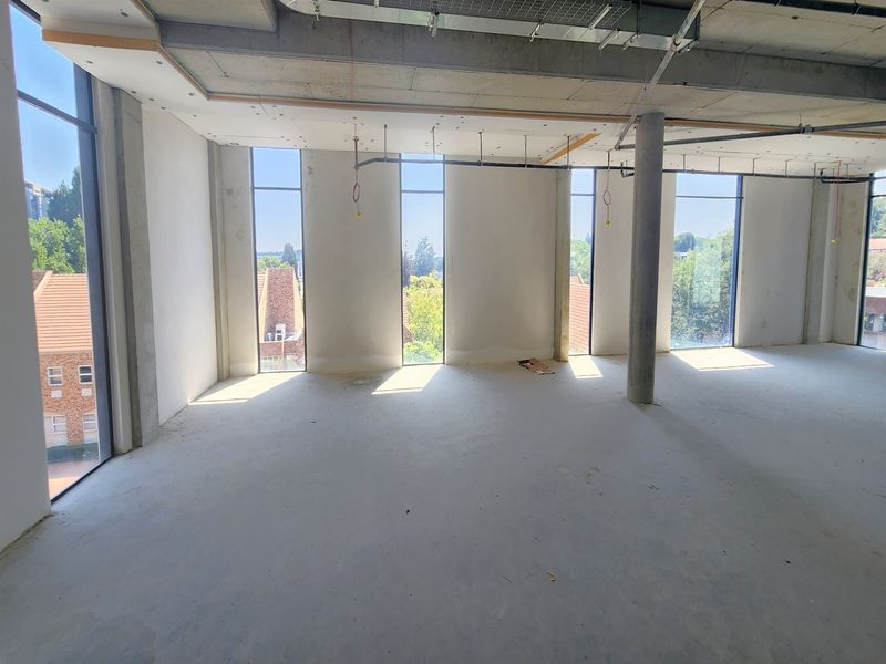 An open-plan office space in shell condition featuring floor-to-ceiling windows, exposed concrete ceilings, and structural columns, ready for custom fit-out.