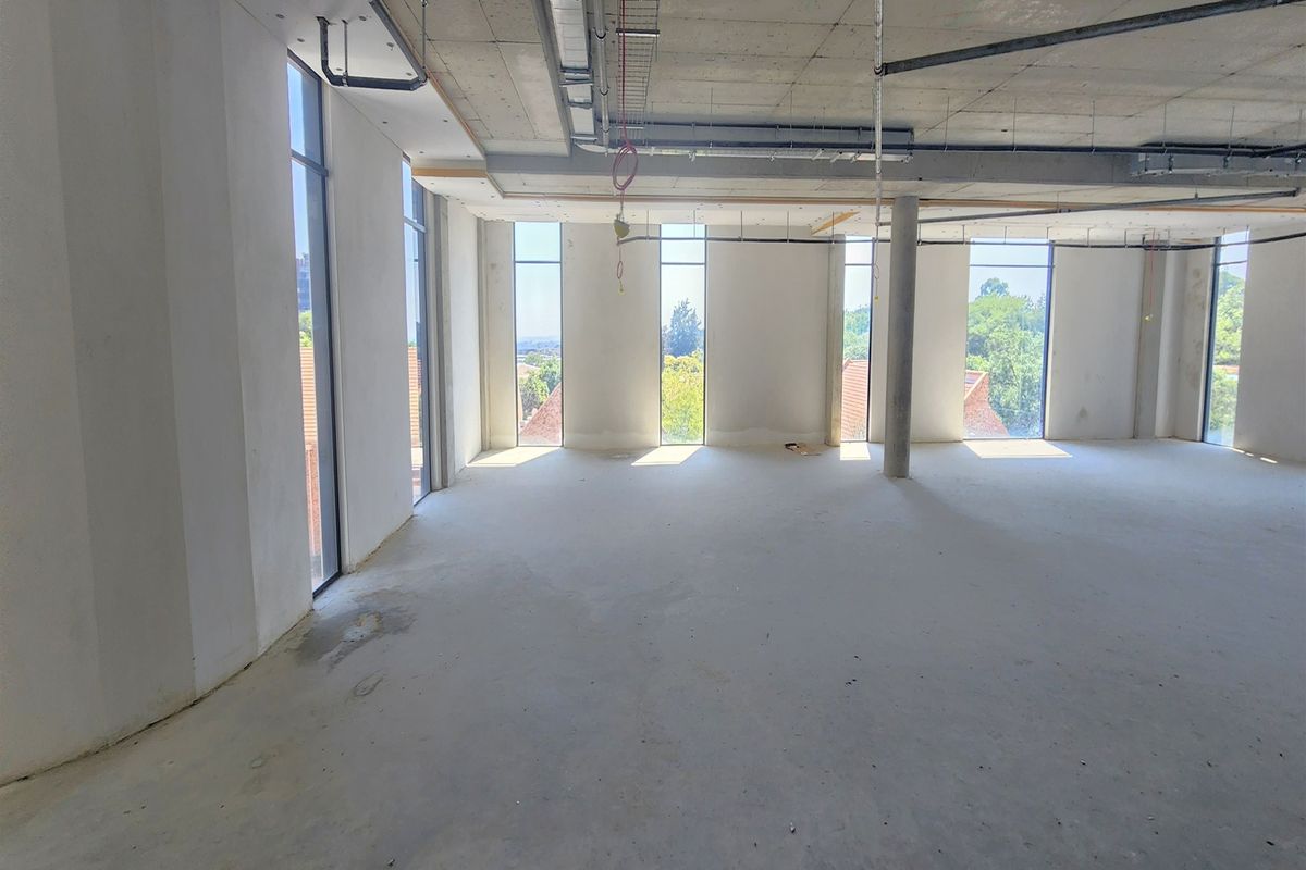An open-plan office space in shell condition, featuring exposed concrete ceilings, floor-to-ceiling windows, and natural light, ready for custom fit-out.