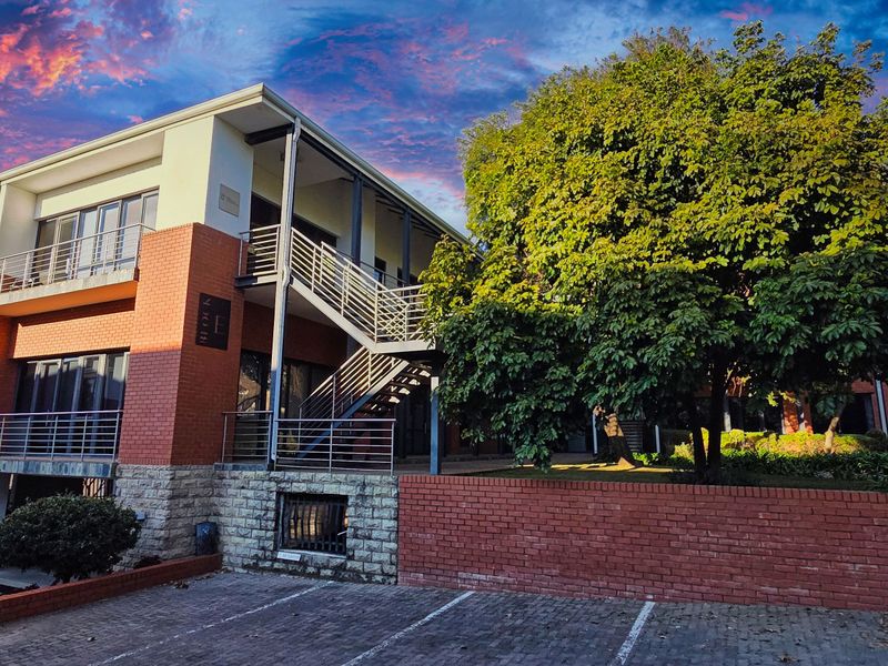 A multi-story office building featuring a brick and stone facade, external staircase, and dedicated paved parking area.