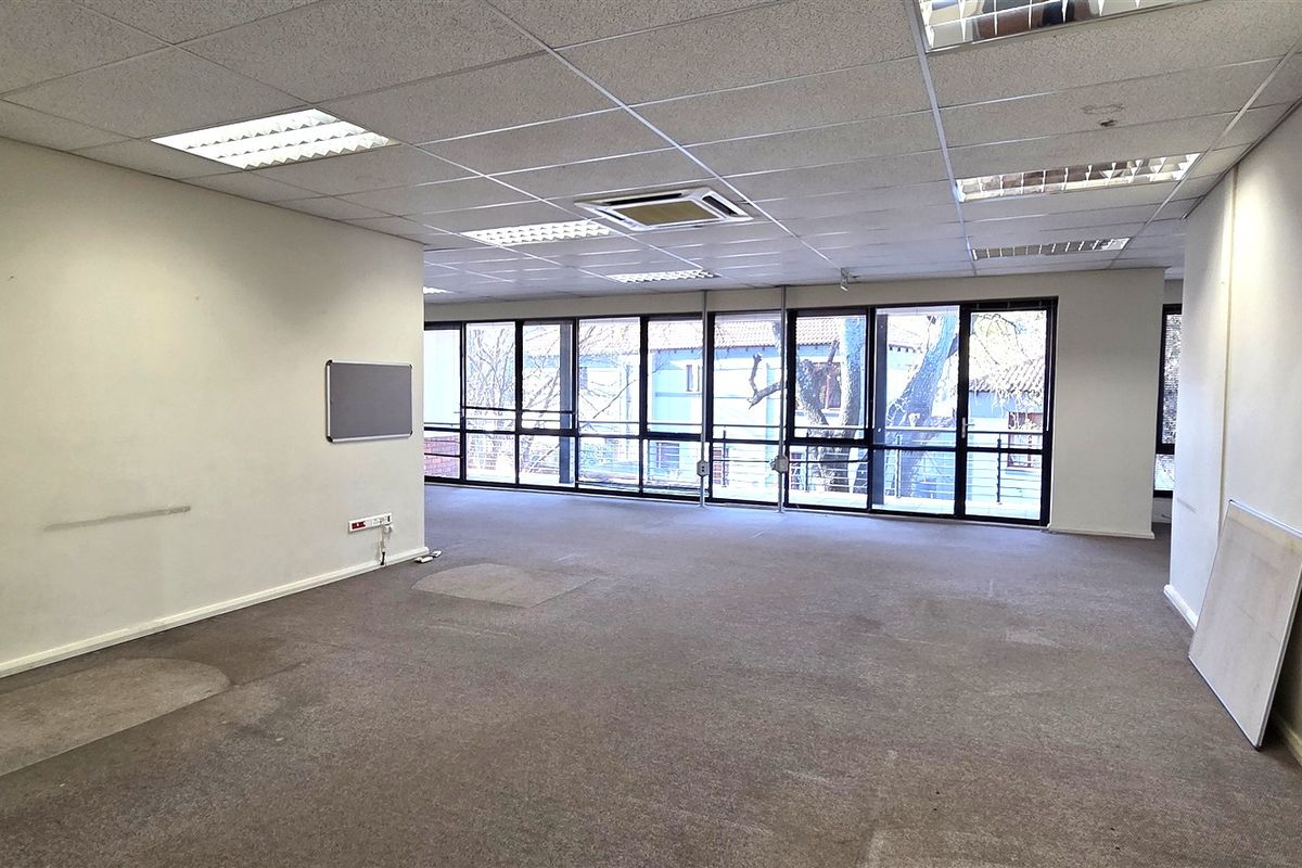 Spacious open-plan office area featuring large windows for natural light, suspended ceilings with integrated lighting, and central air conditioning.