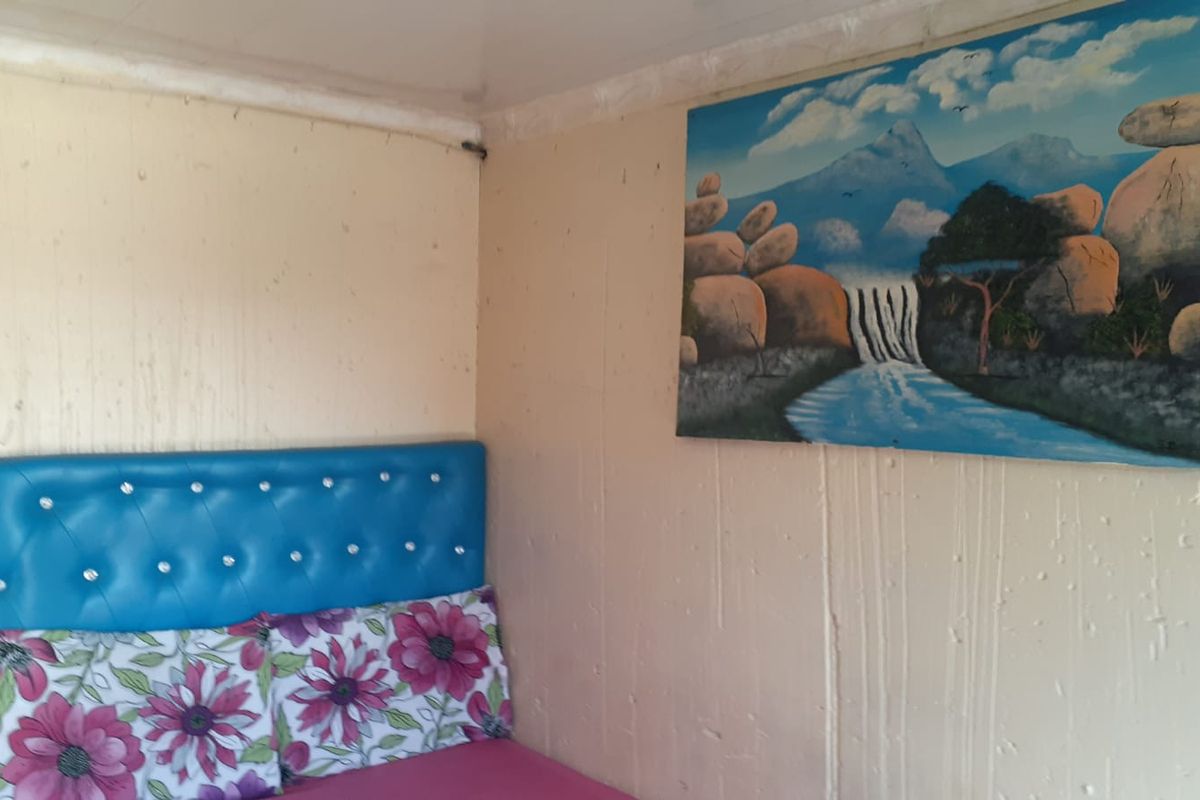 A bedroom interior featuring basic wall paneling and a corner placement for a bed.