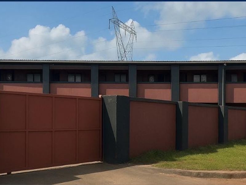A view of the lodge exterior featuring a secure gated entrance, perimeter boundary wall, and multi-level building structure with dark-toned facade finishes.