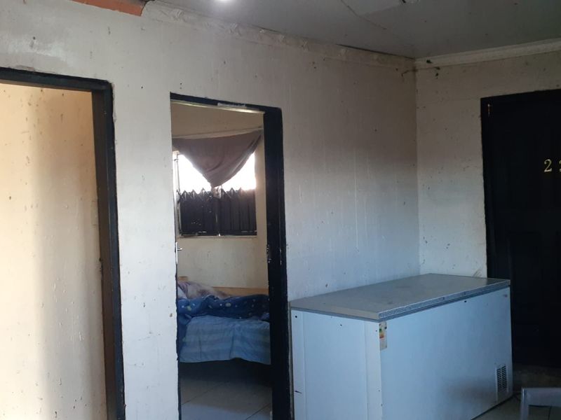 Interior view of a lodge room featuring multiple doorways, basic wall finishes, and a chest freezer in a functional, dated space.