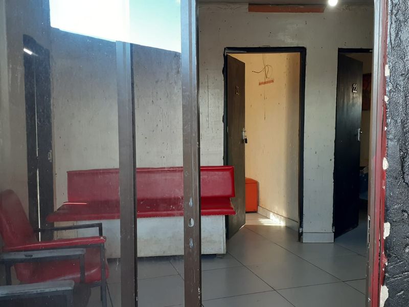 A view into a lodge hallway or reception area featuring tiled flooring, multiple doorways, and basic wall finishes in need of maintenance.