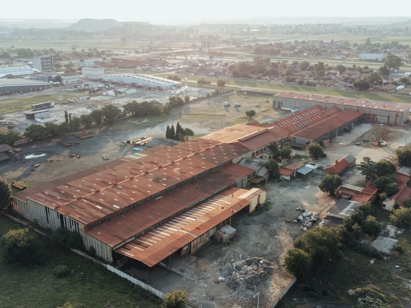 Aerial view of a large industrial warehouse complex featuring extensive metal roofing and surrounding yard space in an industrial zone.