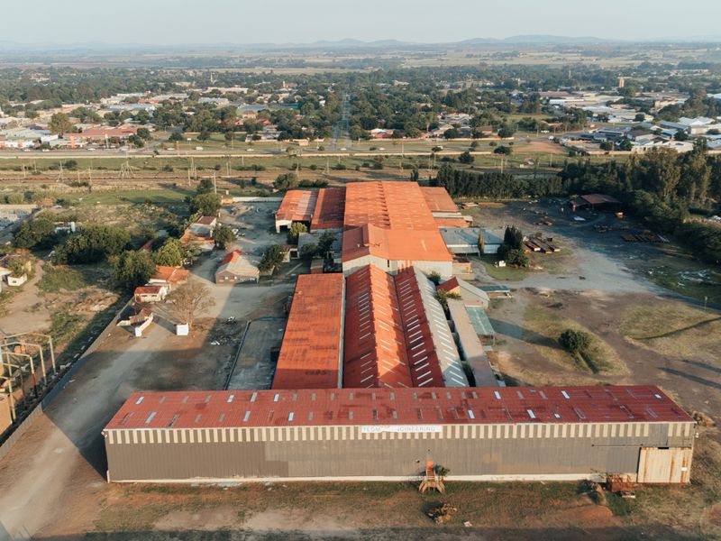 Aerial view of a large industrial facility featuring extensive metal roofing and expansive yard space, situated within a commercial industrial zone.