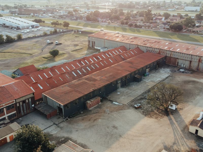 Aerial view of an industrial property featuring large warehouse structures with extensive metal roofing and expansive yard space.
