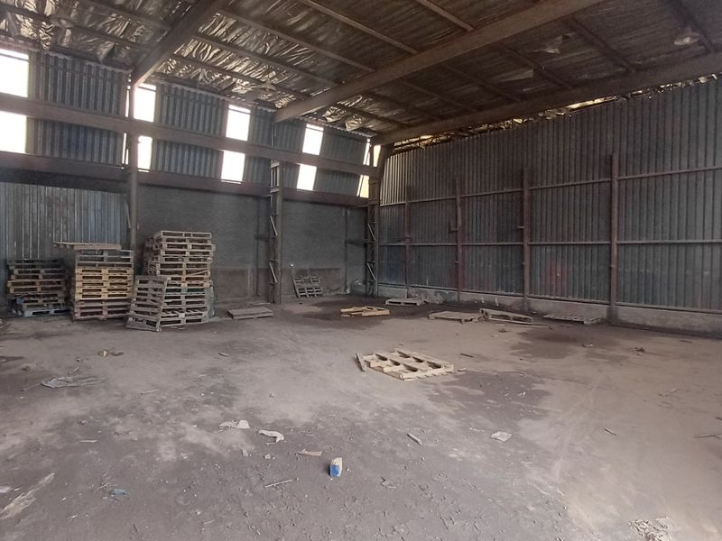 Spacious industrial warehouse featuring high ceilings, corrugated metal walls, and a large open floor plan suitable for storage or manufacturing operations.