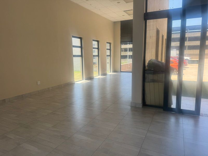 Spacious open-plan retail area featuring large windows, tiled flooring, and a suspended ceiling, offering a bright and versatile commercial space.