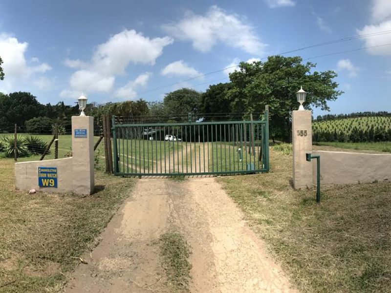 A gated entrance to the property featuring metal security gates, masonry pillars, and perimeter fencing set within a rural landscape.
