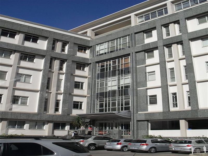 A multi-story office building facade featuring granite cladding, large glass window panels, and a covered entrance area.
