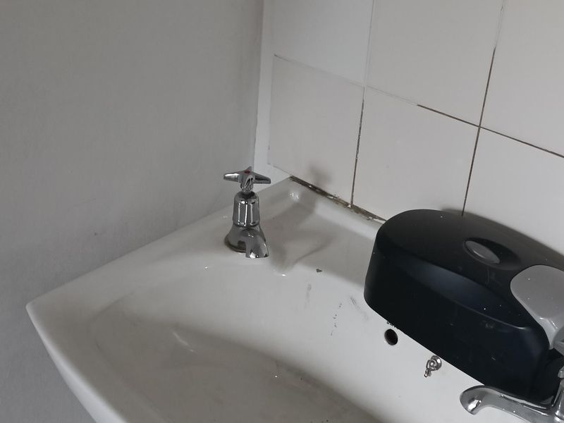 A functional industrial-style hand wash basin featuring a wall-mounted faucet and tiled splashback, suitable for utility or washroom areas.