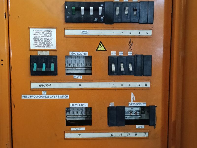 Industrial electrical distribution board featuring multiple 380V socket connections and circuit breakers, showing signs of wear and missing protective covers.