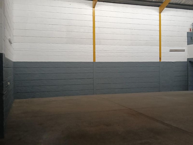 Spacious industrial warehouse interior featuring high ceilings, exposed steel support beams, and durable concrete flooring, suitable for storage or manufacturing operations.