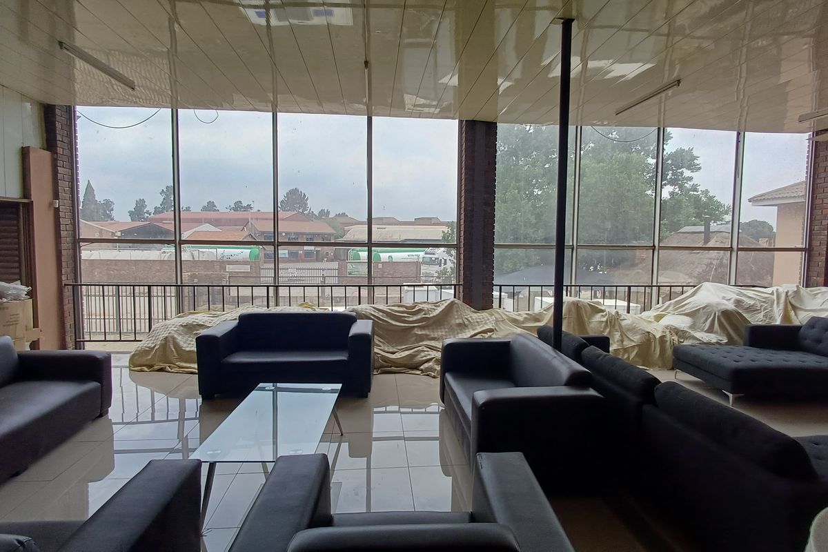 Spacious industrial-style lounge area featuring floor-to-ceiling glass windows, tiled flooring, and a high-gloss suspended ceiling.