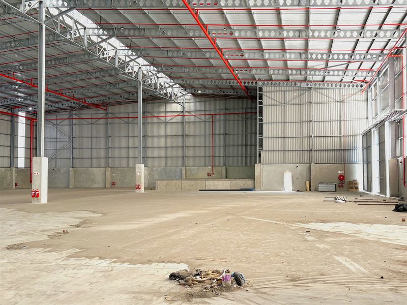 Spacious industrial warehouse featuring a high-clearance steel portal frame, concrete flooring, and an integrated fire sprinkler system.