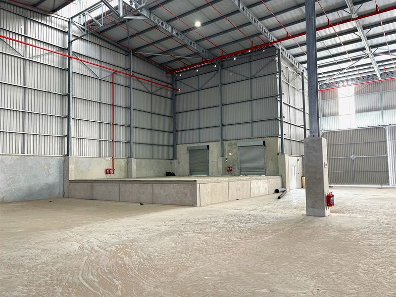 Spacious industrial warehouse featuring a raised loading dock, roller shutter doors, high-clearance steel roof structure, and integrated fire safety systems.