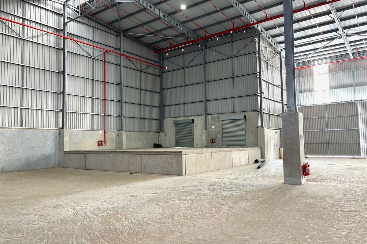 Spacious industrial warehouse featuring a raised loading dock, roller shutter doors, high-clearance steel roof structure, and integrated fire safety systems.