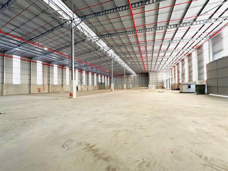 Expansive industrial warehouse space featuring high ceilings, steel portal frame construction, integrated sprinkler system, and abundant natural light through skylights.