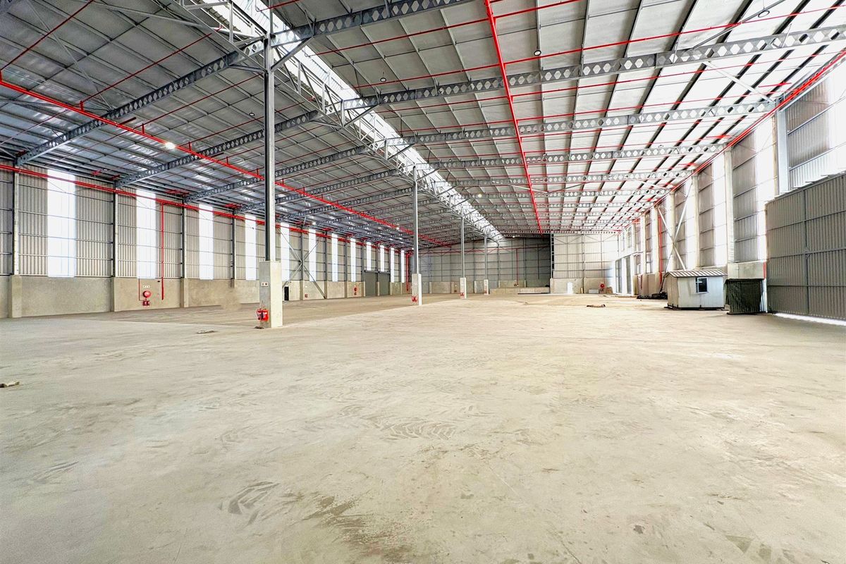 Expansive industrial warehouse space featuring high ceilings, steel portal frame construction, integrated sprinkler system, and abundant natural light through skylights.