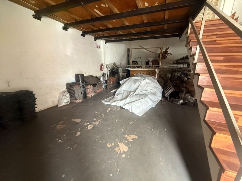 Industrial utility space featuring exposed timber ceiling beams, a wooden staircase, and concrete flooring, suitable for storage or workshop use.