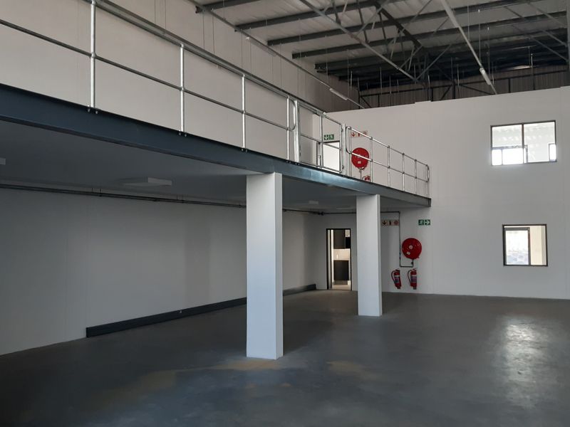 Spacious industrial warehouse unit featuring a mezzanine level, epoxy flooring, and high-clearance ceilings with exposed steel trusses.
