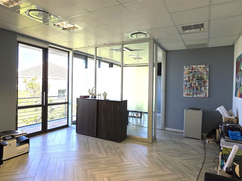 Modern office space featuring herringbone tile flooring, a glass partition wall, and recessed lighting, providing a bright and professional work environment.