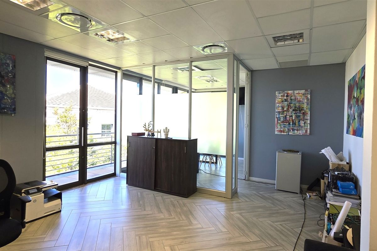Modern office space featuring herringbone tile flooring, a glass partition wall, and recessed lighting, providing a bright and professional work environment.