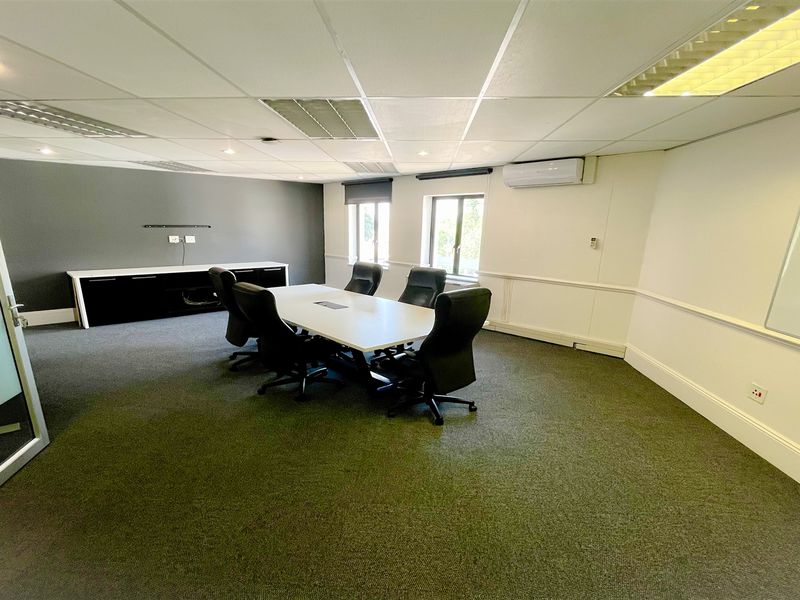 A professional office meeting room featuring a suspended ceiling, integrated air conditioning, built-in storage cabinetry, and a glass partition entrance.