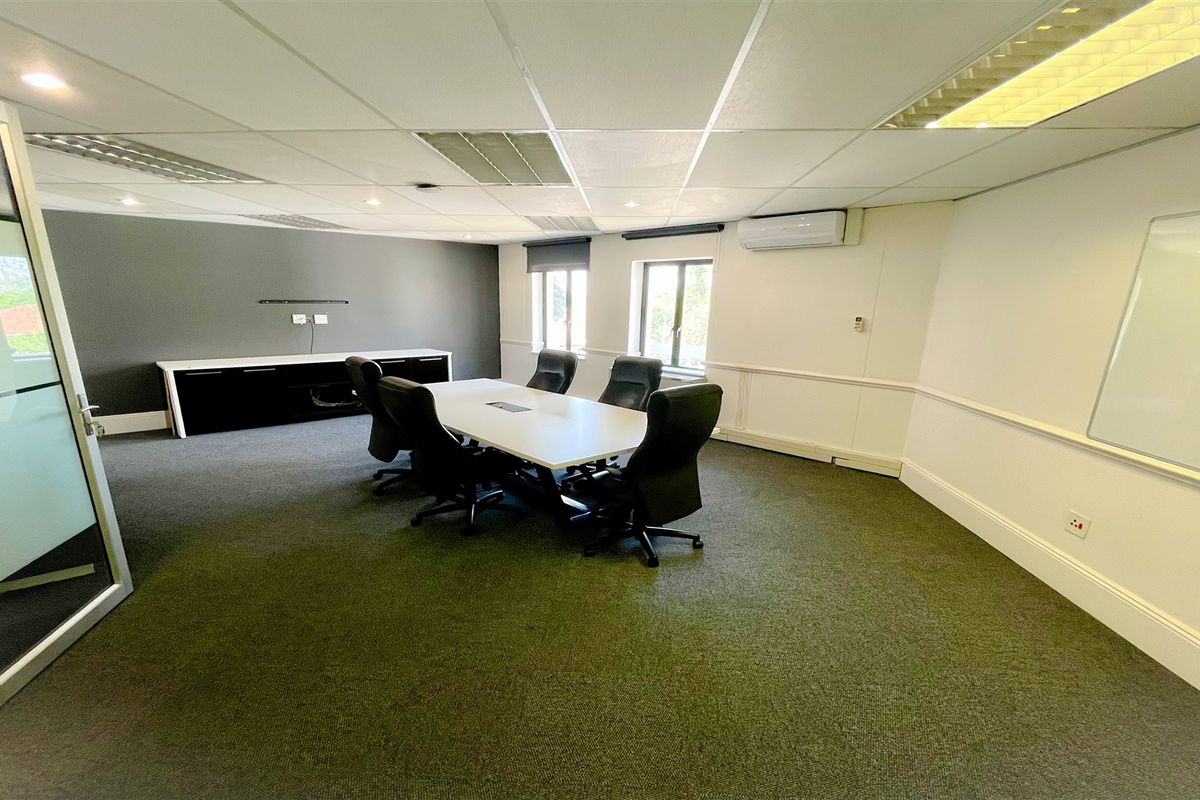 A professional office meeting room featuring a suspended ceiling, integrated air conditioning, built-in storage cabinetry, and a glass partition entrance.