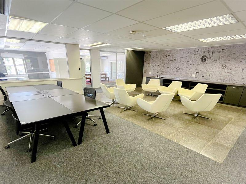A spacious office area featuring a mix of carpet and tiled flooring, recessed lighting, built-in cabinetry, and a glass partition wall.