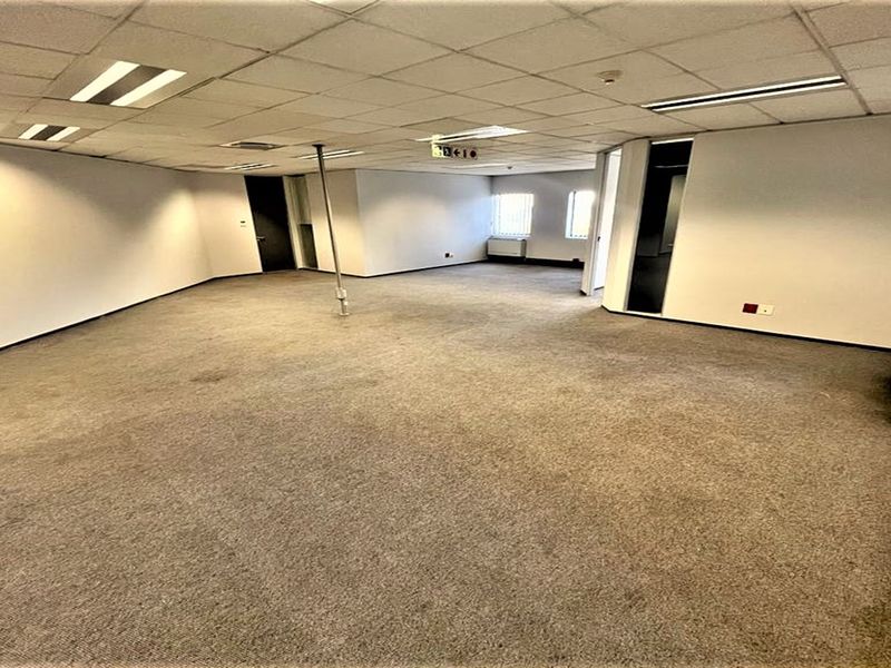 An empty, open-plan office space featuring a suspended ceiling, recessed lighting, and carpeted flooring, ready for custom fit-out.