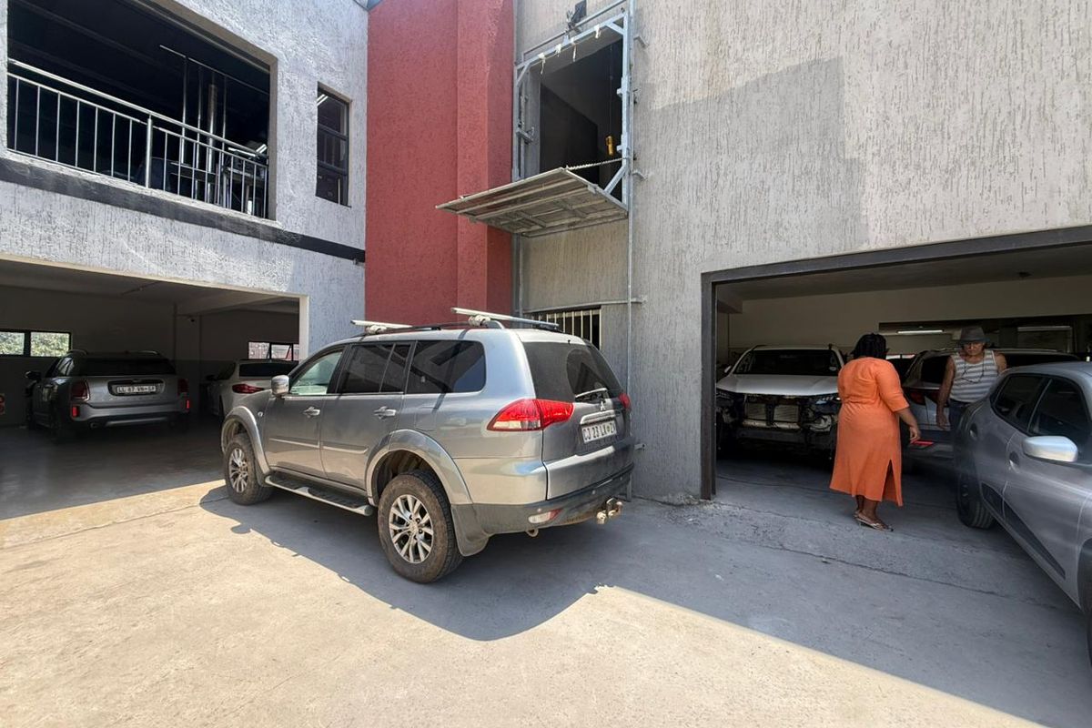 Exterior view of an industrial property featuring multiple garage bays, a loading platform, and a paved courtyard area.