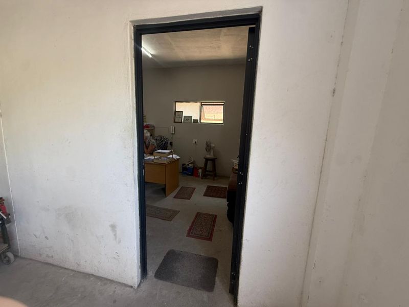 A view through a doorway into a functional office space with concrete flooring and a small window.