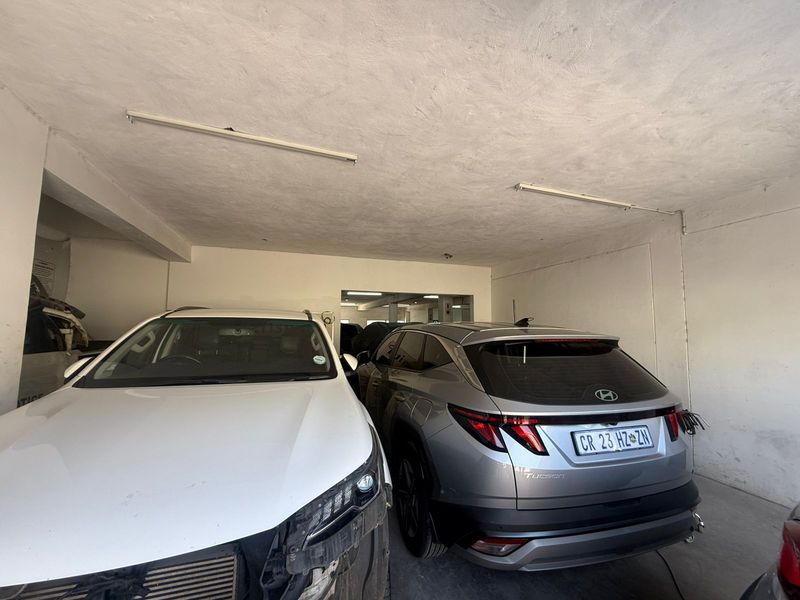 A functional industrial garage space featuring concrete flooring and overhead strip lighting, suitable for vehicle storage or workshop use.