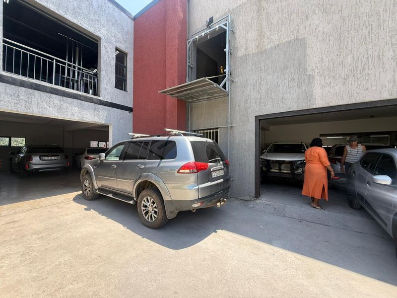 Exterior view of an industrial property featuring multiple garage bays, a loading platform, and a paved courtyard area.